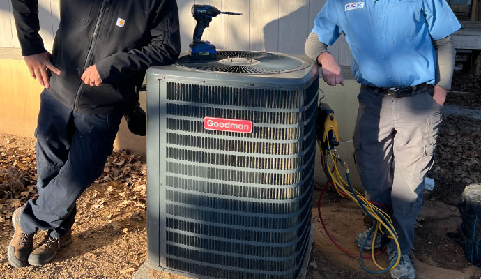 Experts standing beside an installed HVAC unit